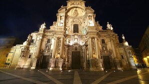 Um edifício imponente e iluminado, com detalhes arquitetônicos elaborados e estátuas.