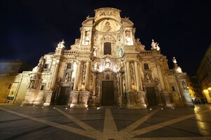 A grand, illuminated building with intricate architectural details and statues.