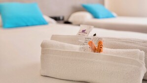 A hotel room with two beds, each with a blue pillow, and a neatly folded white towel on the bed.