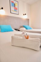 A hotel room with two beds, each with a blue pillow, and a neatly folded white towel on the bed.