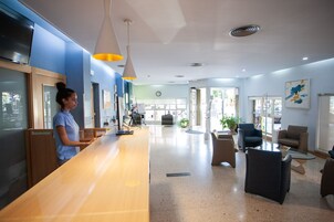 A reception area with a wooden counter, blue walls, and a seating area with chairs and a coffee table.