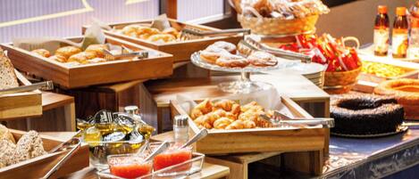 A buffet with various food items including pastries, fruits, and beverages.