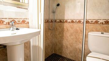 A bathroom with a shower, sink, toilet, and a mirror.