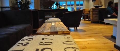 Un rincón de sala acogedor con una mesa de madera alargada, asientos acolchados y un velero decorativo en la pared.