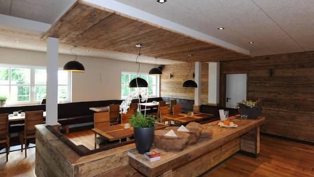 Un interior moderno con detalles de madera, una zona de estar central e iluminación colgante.