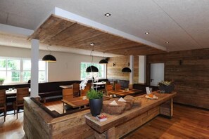 Un interior moderno con detalles de madera, una zona de estar central e iluminación colgante.