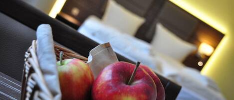 Een mand met appels op een tafel, met een bed op de achtergrond.