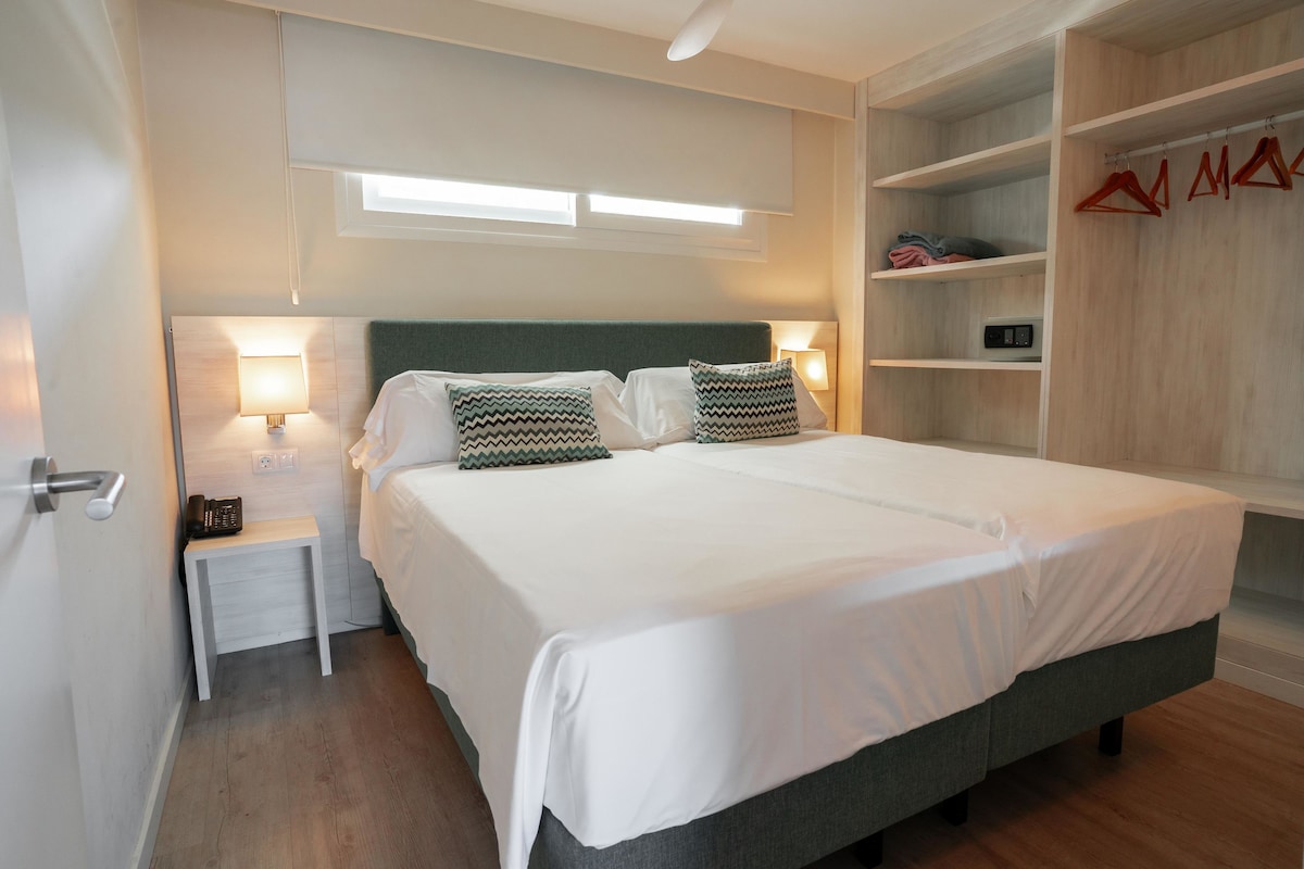 A bedroom with a bed, bedside tables, a wardrobe, and a window.