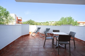 A terrace with a table and chairs, a view of buildings and trees, and a tiled floor. - INN Mallorca Aparthotel (Calvia)