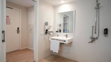 Een moderne badkamer met een witte wastafel, een spiegel, een handdouche en een handdoek aan de muur.
