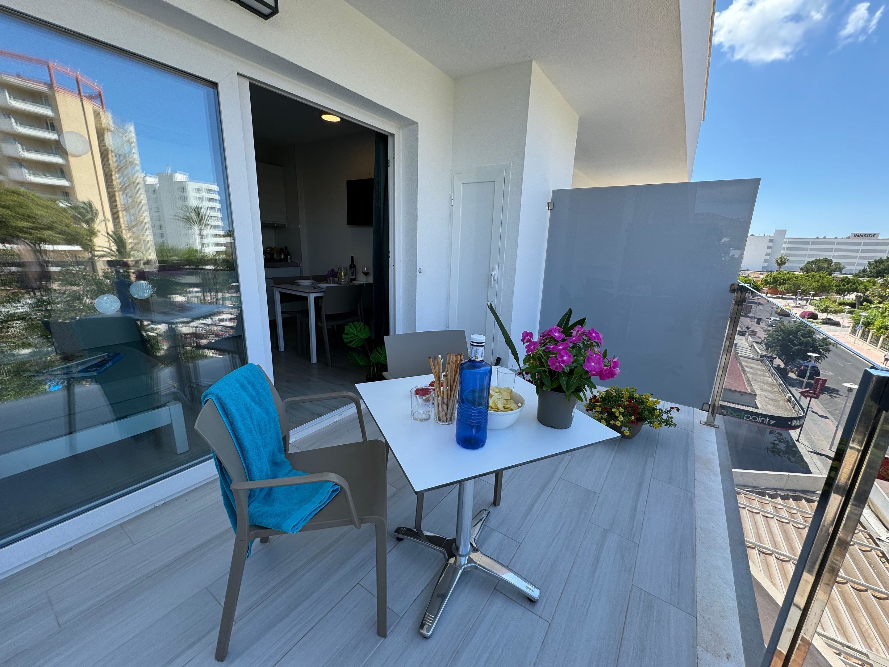 Un balcon avec une table, une chaise et des plantes en pot.