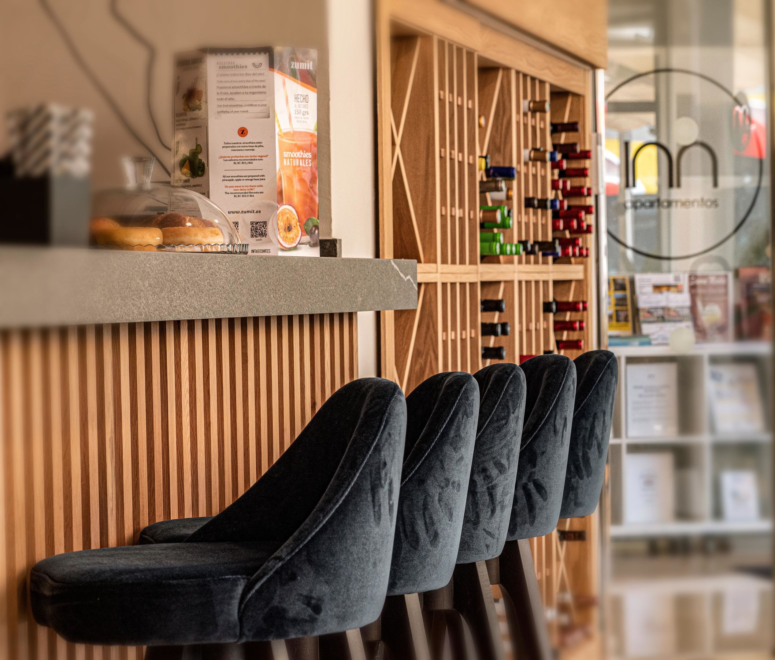 A bar area with a wooden slat wall, a counter with a QR code, and a wine rack in the background.