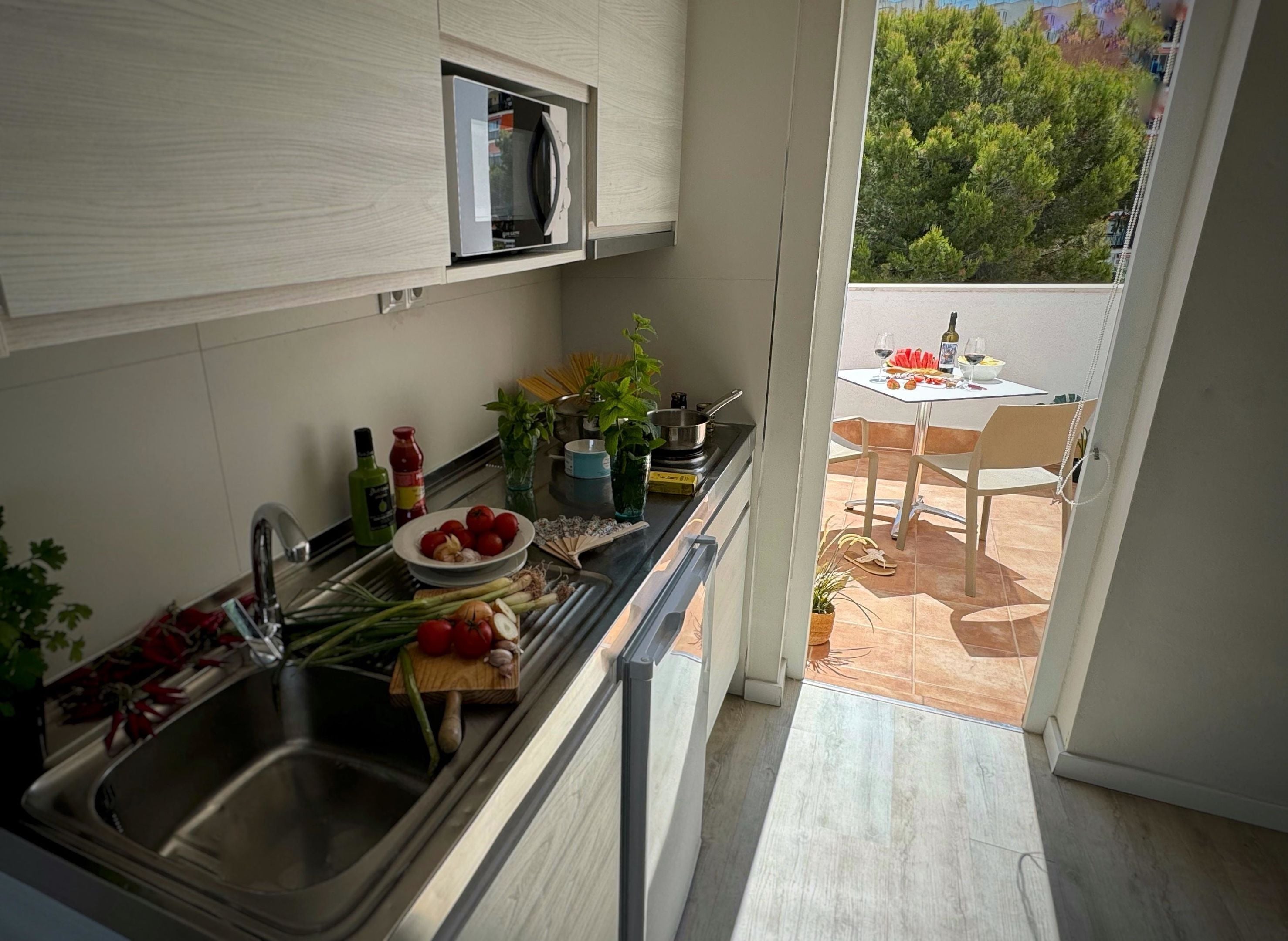 Una cocina moderna con microondas integrado, un lavamanos y una zona de comedor con mesa y sillas.