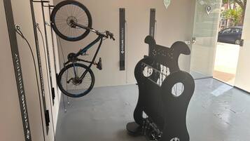 Una bicicleta colgada en un soporte de pared, un atril para reparación de bicicletas y una puerta con el símbolo de una bicicleta.