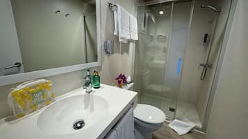 A modern bathroom with a white sink, a toilet, and a glass-enclosed shower.