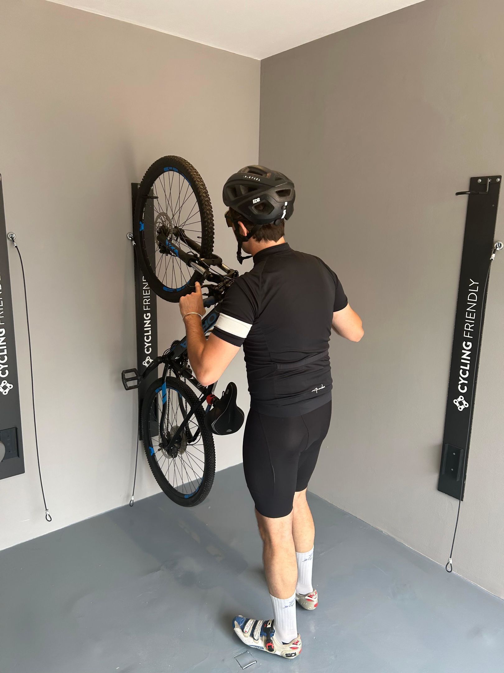 A person mounting a bicycle on a wall-mounted bike rack.