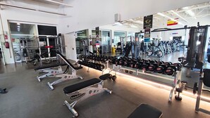 A gym with various exercise equipment, including benches, dumbbells, and weight machines. -  Alannia Costa Blanca Resort (Crevillente)