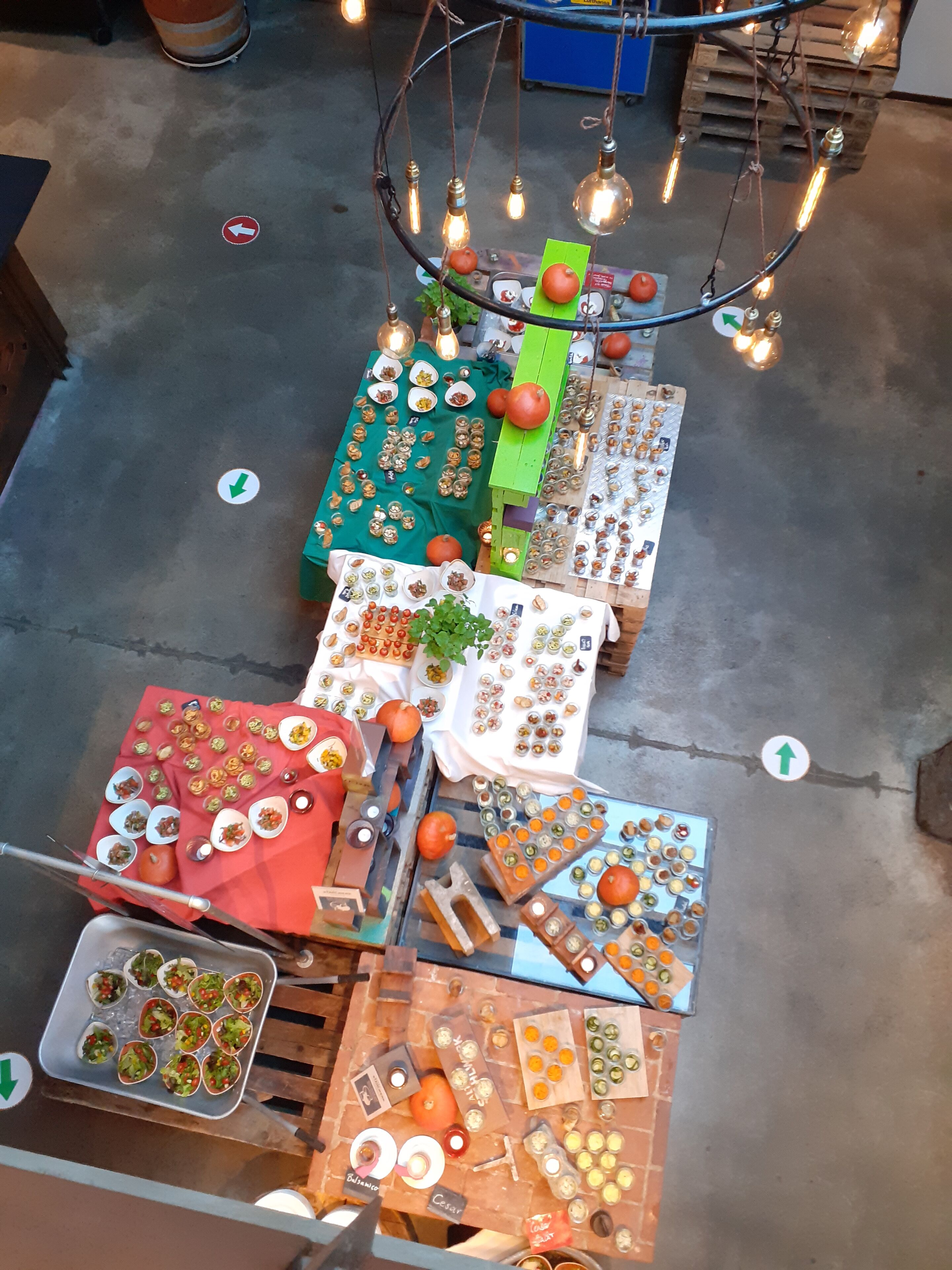 A variety of food items and decorations displayed on tables and stands, with directional arrows on the floor.