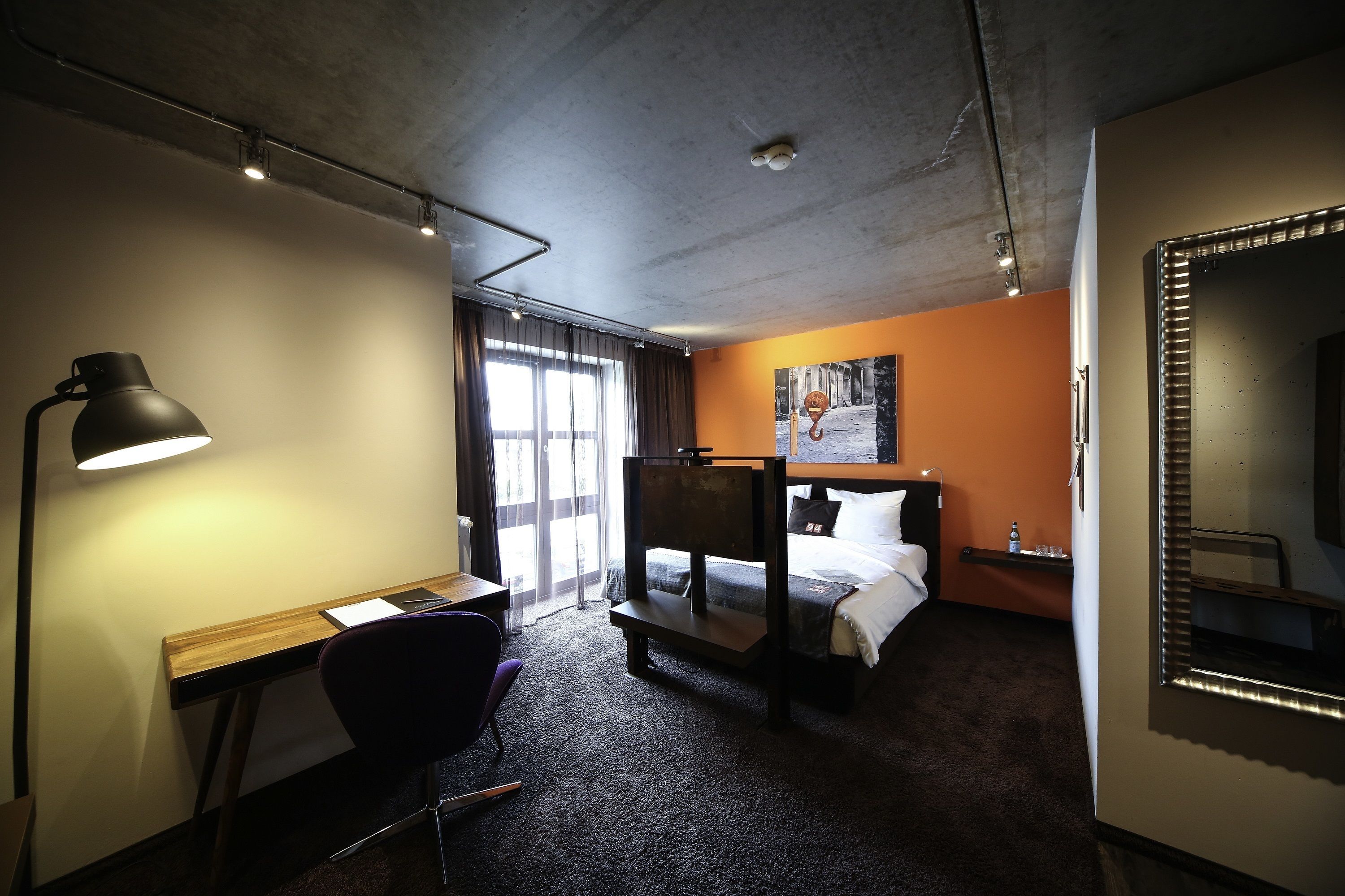 Ett hotellrum med ett skrivbord, en stol, våningssängar och en stor spegel.