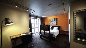 Ett hotellrum med ett skrivbord, en stol, våningssängar och en stor spegel.