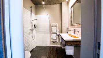 Een moderne badkamer met douche, toilet en wastafel.