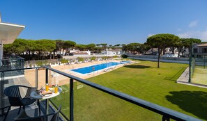 Zona de piscina amb una piscina blava cristal·lina, gandules i gespa.