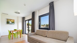 Una sala de estar moderna con un sofá color beige, una mesa de centro de madera y un comedor con mesa y sillas.
