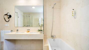 A bathroom with two sinks, a large mirror, a shower, and a hairdryer on the wall.