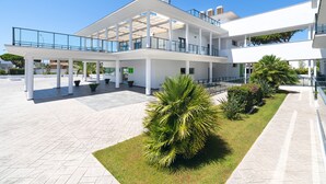 Un edificio moderno con un área exterior cubierta, varios niveles y un jardín central con palmeras.