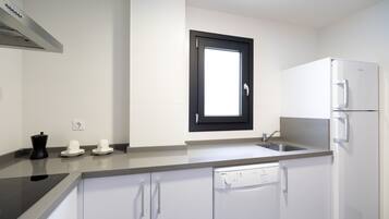 Eine moderne Küche mit Geschirrspüler, Backofen und einem Fenster über der Spüle.