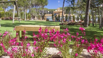 Sit on a bench surrounded by lush greenery and vibrant flowers in a serene outdoor setting.