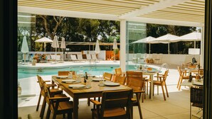 An outdoor dining area with tables and chairs, a pool, and umbrellas. - Ses Eufabietes Apartments & Restaurant (Formentera)