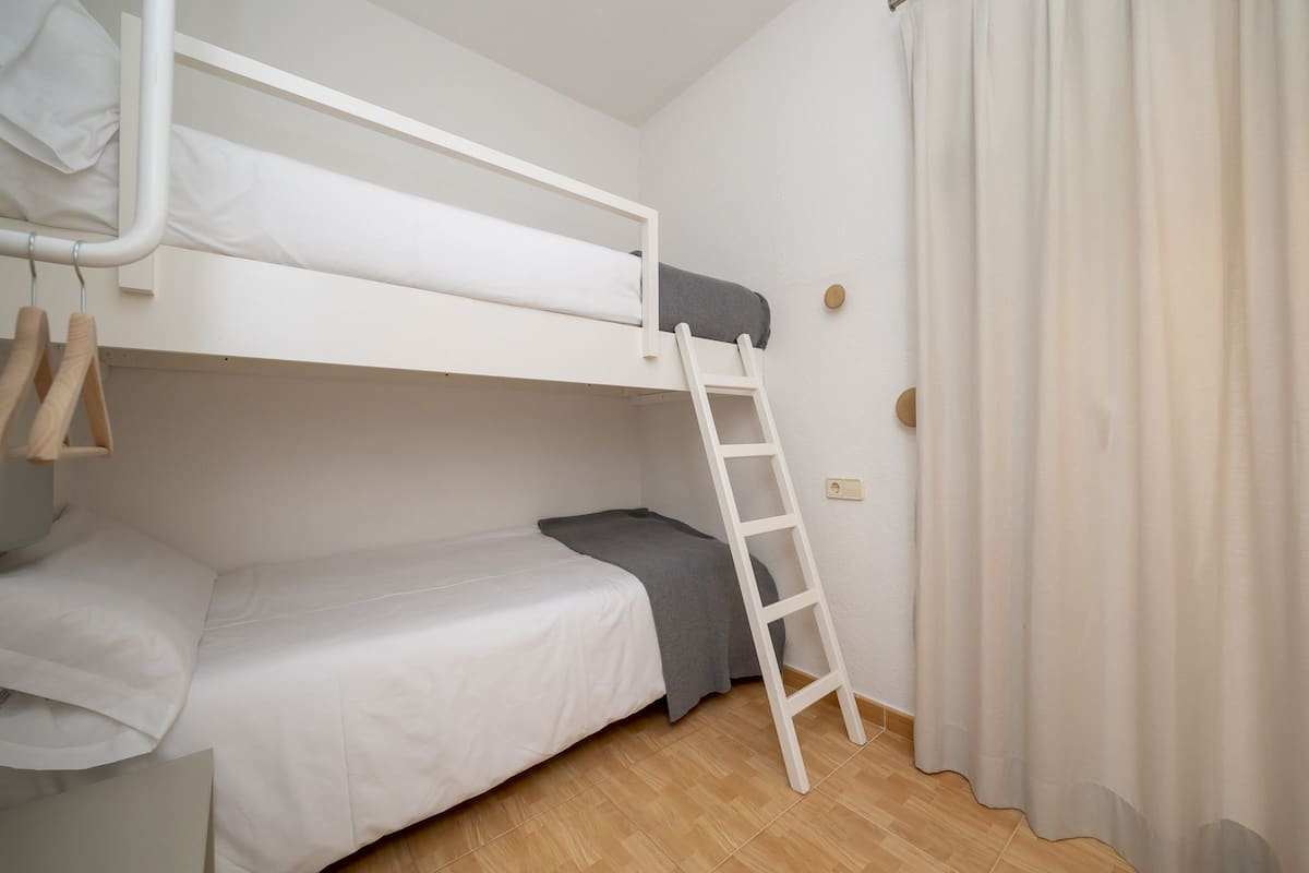 Ein Schlafraum mit Etagenbetten, einer kleinen Nachttisch und einem Vorhang.