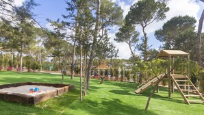 A playground with a sandpit, wooden climbing structures, and a covered play area. - Ses Eufabietes Apartments & Restaurant (Formentera)