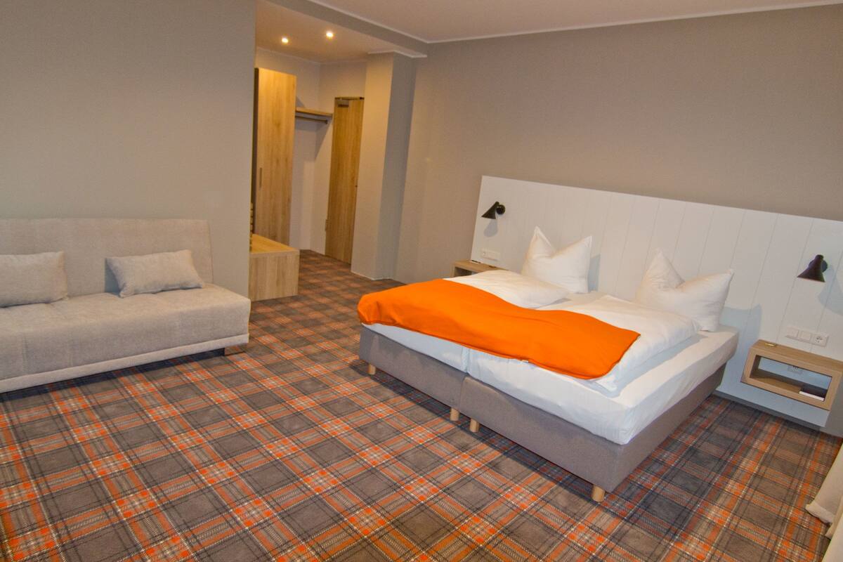 Una habitación de hotel con una cama, un sofá y suelo estampado de pata de gallo.