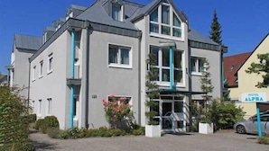 A two-story hotel with a grey facade, large windows, and a balcony. - Hotel Alpha (Nuremberg)