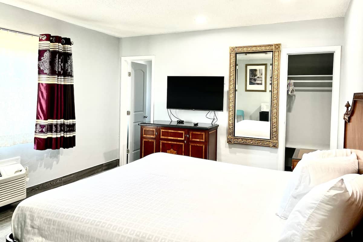 A hotel room with a bed, a television, a wardrobe, and a mirror.
