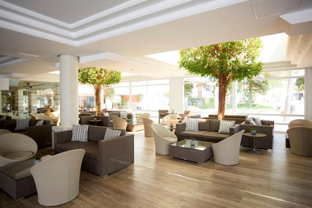 A spacious lobby with modern furniture, large windows, and indoor trees.