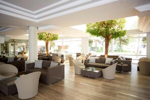 A spacious lobby with modern furniture, large windows, and indoor trees. - Es Pi2 (Formentera)