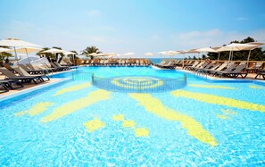 A large pool with multiple sun loungers and umbrellas, surrounded by palm trees and a clear sky. - Es Pi2 (Formentera)