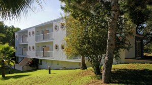 Un immeuble à plusieurs étages doté de balcons, entouré d’arbres et d’herbe.