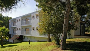 A multi-story building with balconies, surrounded by trees and grass. - Es Pi2 (Formentera)