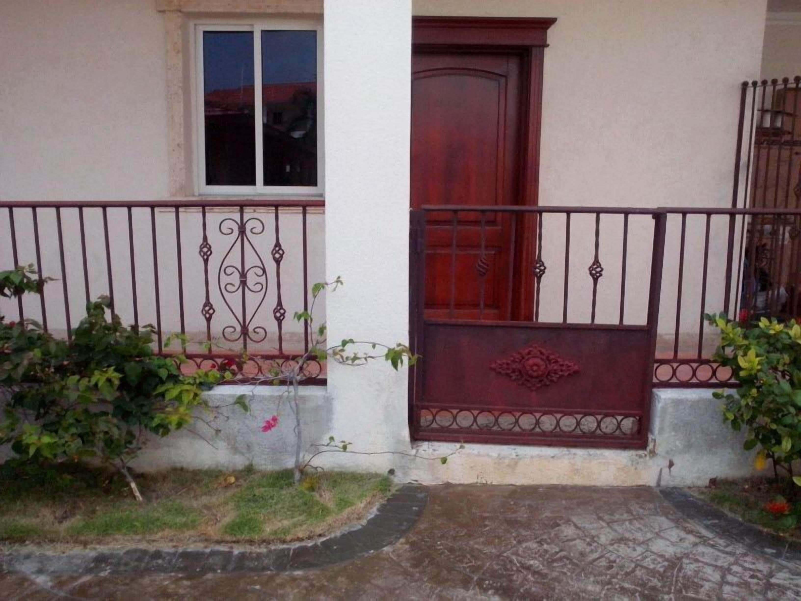 A house with a red door, a window, and a metal gate.