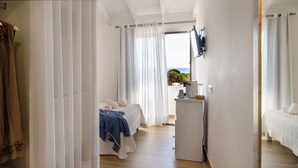 A hotel room with a bed, a desk with a coffee maker, and a view of the outdoors. - Hotel Rosamar (Formentera)