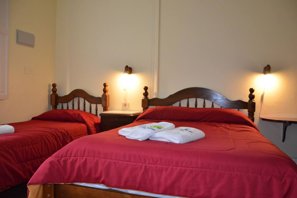 Two single beds with wooden headboards, red bedding, and bedside lamps.