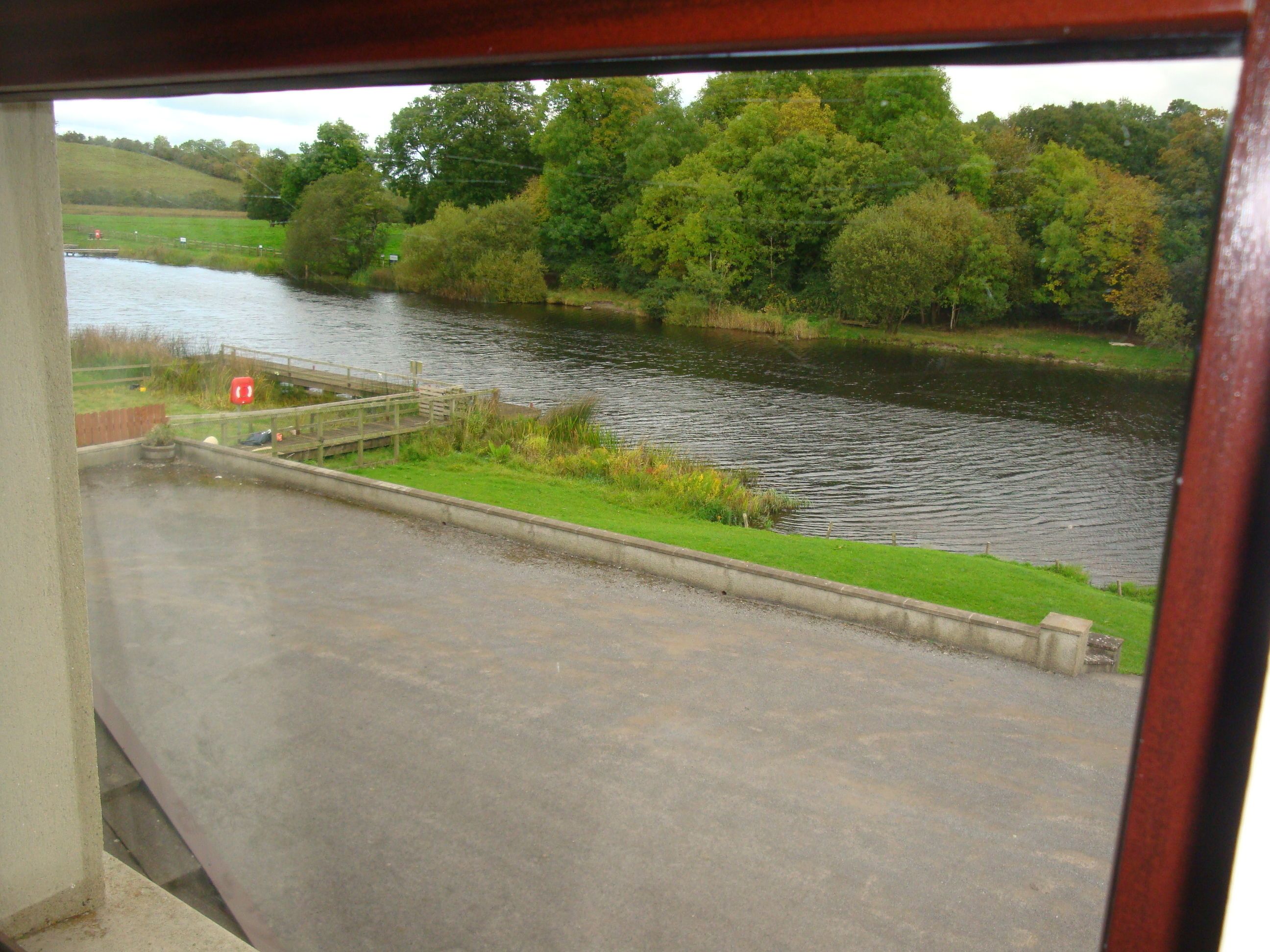 Vista de un río con un puente de madera y una orilla cubierta de hierba.