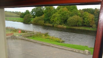 Vista de un río con un puente de madera y una orilla cubierta de hierba.