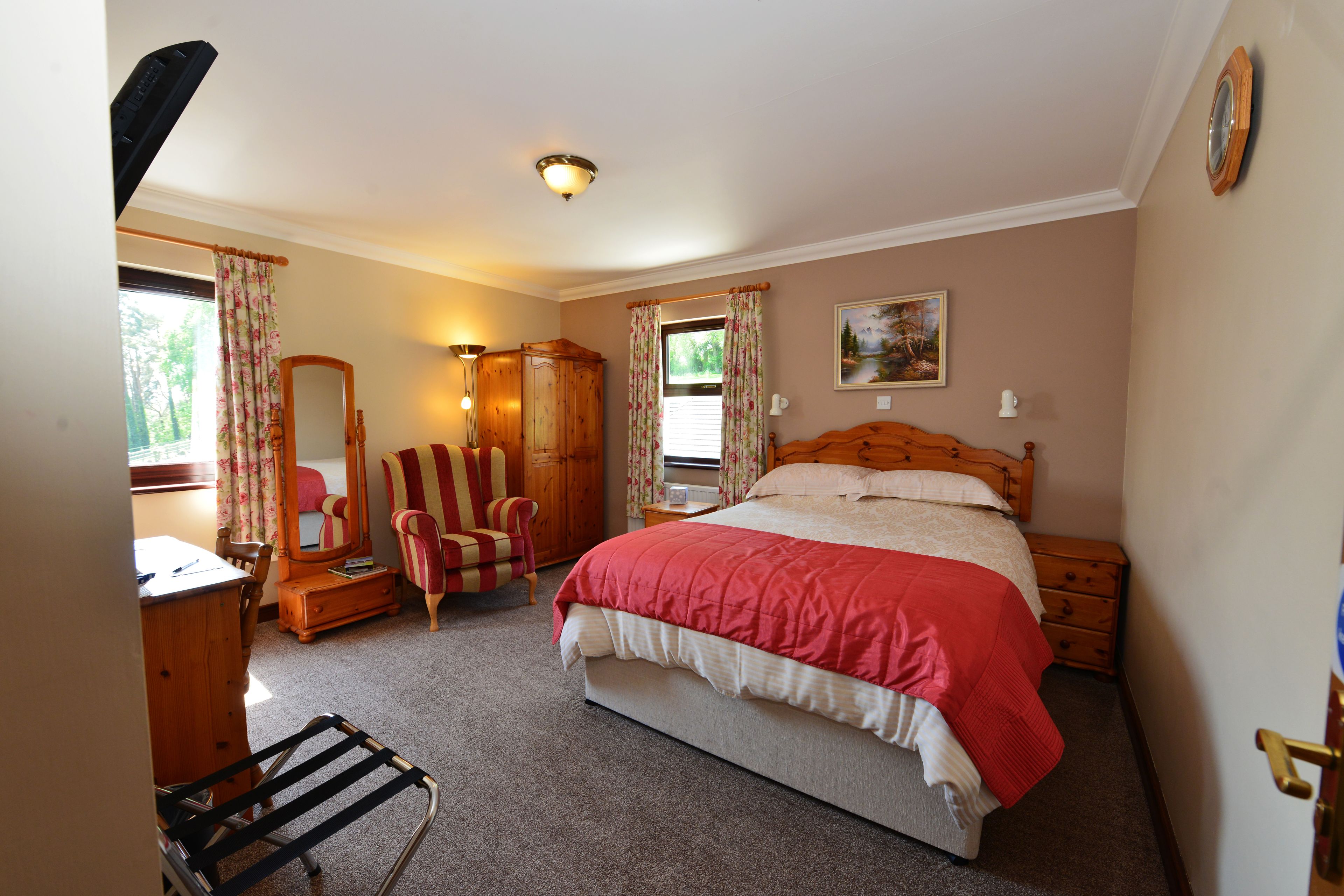 A bedroom with a bed, dresser, chair, and a mirror.