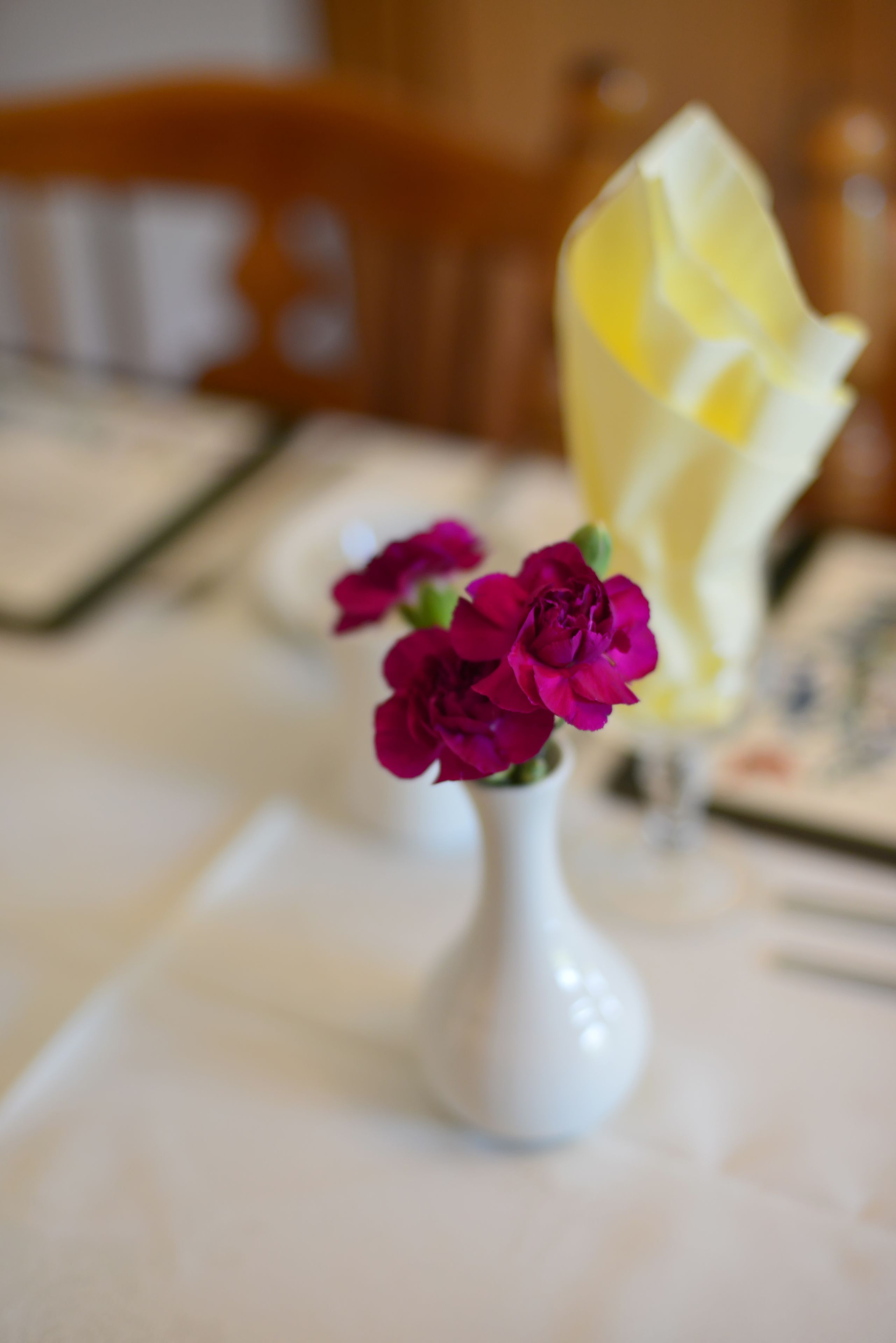 Un jarrón blanco con flores moradas sobre una mesa.