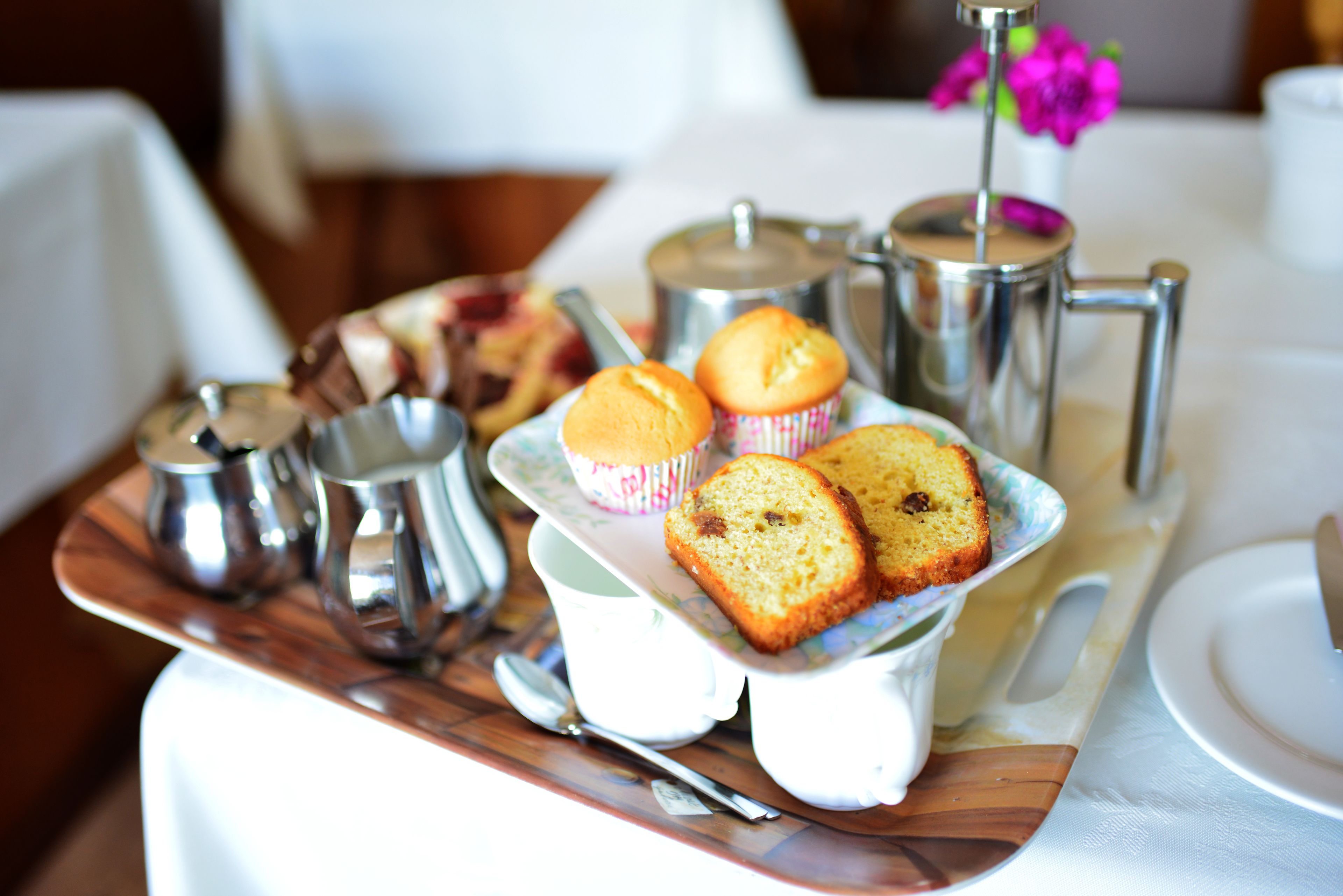 Una bandeja con muffins, una tetera y cubitos de azúcar sobre una mesa.